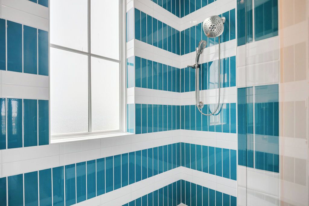 A bathroom with blue and white tiled walls and a shower area.