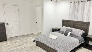 A bedroom with a bed, nightstands, a dresser, and a door. - Downtown McAllen - Sleeps 10 (McAllen)
