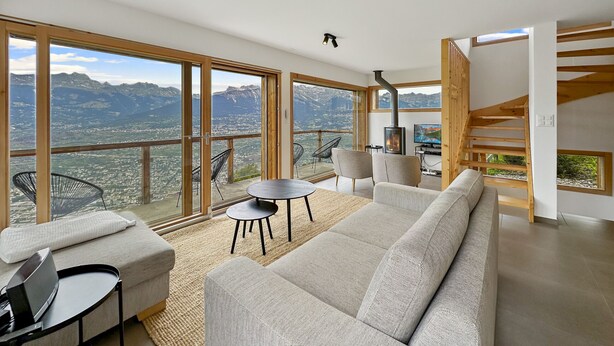 Un salon moderne avec un grand canapé, une petite table et des chaises, une cheminée et un téléviseur.