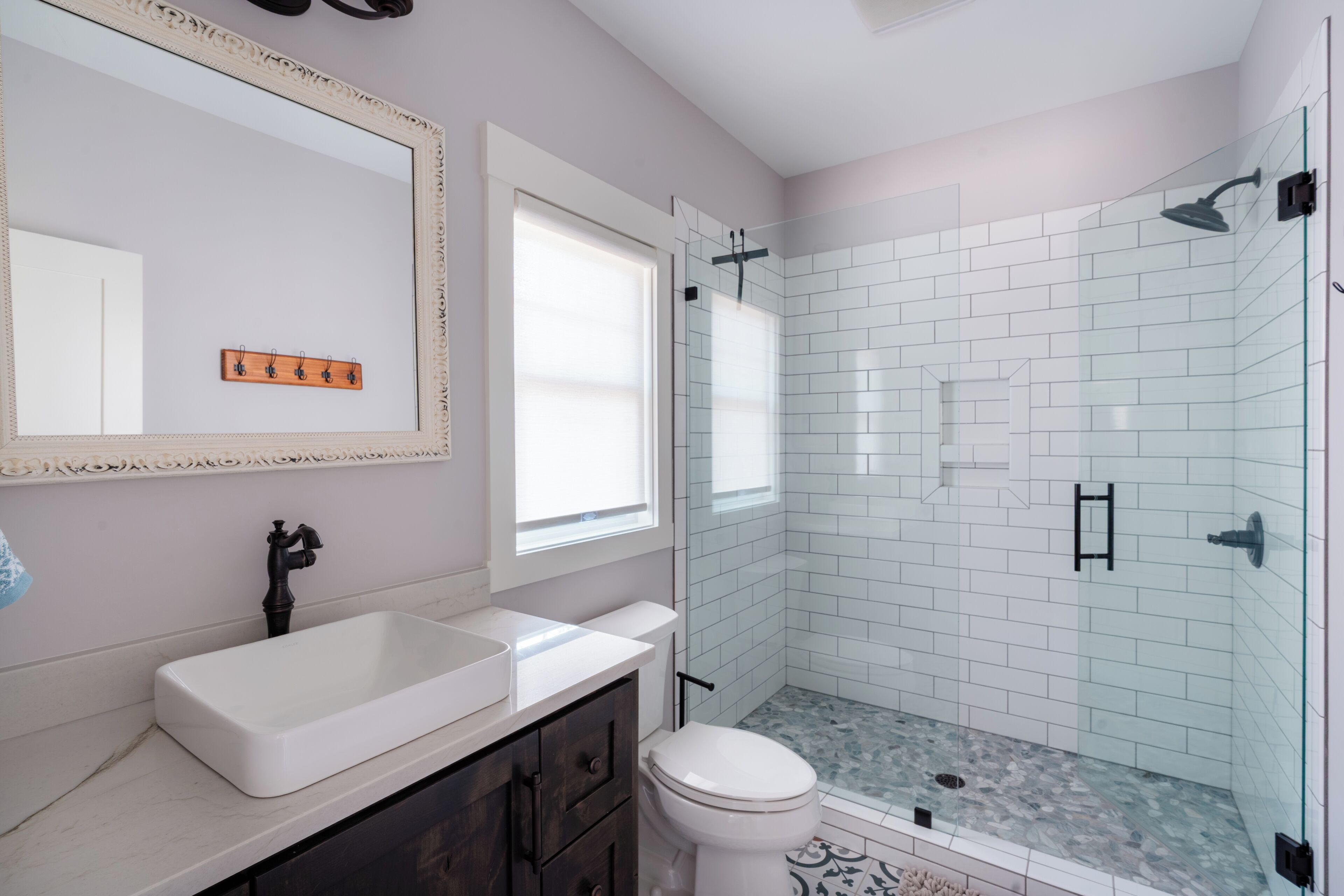 Une salle de bain avec un lavabo blanc, des toilettes et une douche séparée par une paroi de verre.