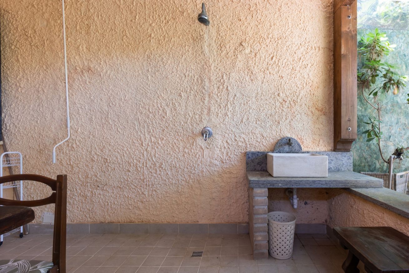 Un baño con pared texturizada, un lavabo, ducha y un banco.