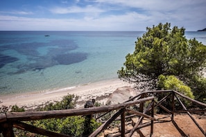 A beach with clear water, a wooden fence, and a tree. - Charming villa of about 80 sqm, able to accommodate up to 4 people, structured on two levels (upper floor accessible by stairs).The property is located inside the Residence Comunione Calaverde, in Santa Margherita di Pula, immersed in the pine forest and (Santa Margherita di Pula)