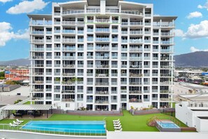 A multi-story hotel with balconies, a swimming pool, and a view of the surrounding area.