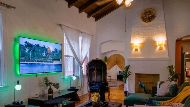 A cozy living room with a flat-screen TV, comfortable seating, a fireplace, and decorative plants. - Edgewater Retreat w/ Pool,Hot Tub,Game Room,+More! (Miami)