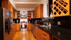 A modern kitchen with wooden cabinets, stainless steel appliances, and a black countertop. - Edgewater Retreat w/ Pool,Hot Tub,Game Room,+More! (Miami)