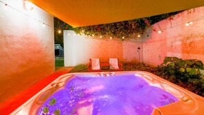 A hot tub with two chairs, surrounded by a wall with string lights and greenery. - Edgewater Retreat w/ Pool,Hot Tub,Game Room,+More! (Miami)