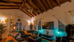 A cozy living room with a large sofa set, a coffee table, and a TV. There is a ceiling fan, a lamp, and a plant. - Edgewater Retreat w/ Pool,Hot Tub,Game Room,+More! (Miami)