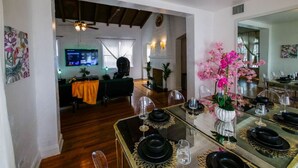 A dining area with a glass table set for six, a mirror on the wall, and a view into the living room. - Edgewater Retreat w/ Pool,Hot Tub,Game Room,+More! (Miami)