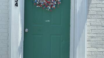 A green door with a wreath, a white door frame, and a number '1234' on the wall.