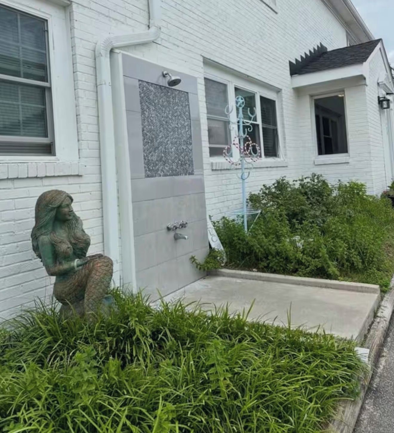 Un edificio blanco con una puerta, un pequeño jardín con césped y una estatua.