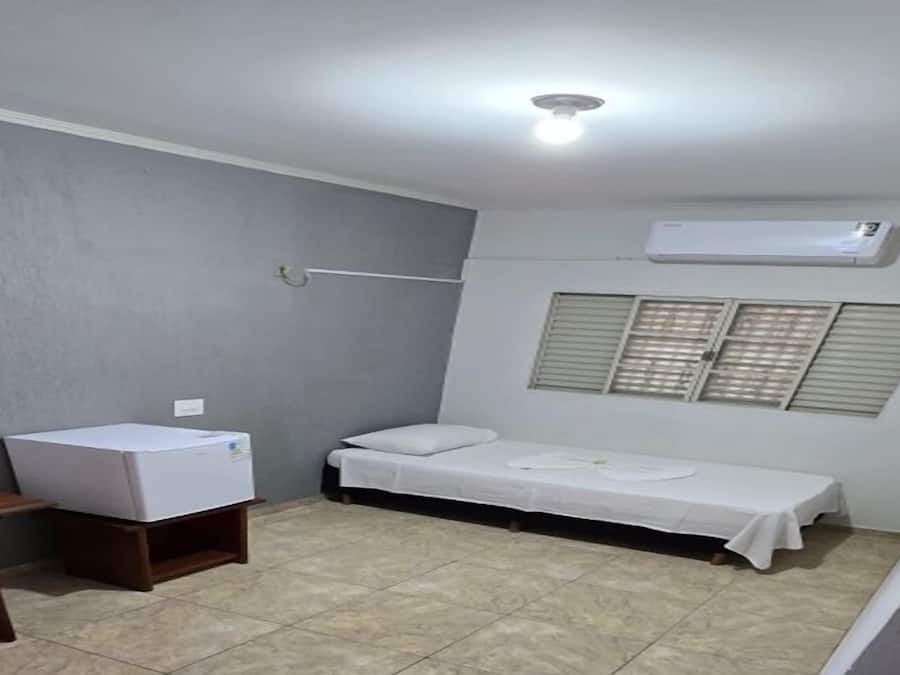 A small, single-room accommodation with a bed, a desk, and a chair.
