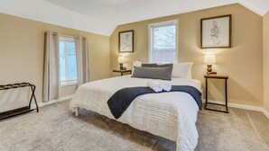 A bedroom with a large bed, two bedside tables with lamps, a radiator, and two framed pictures on the wall.