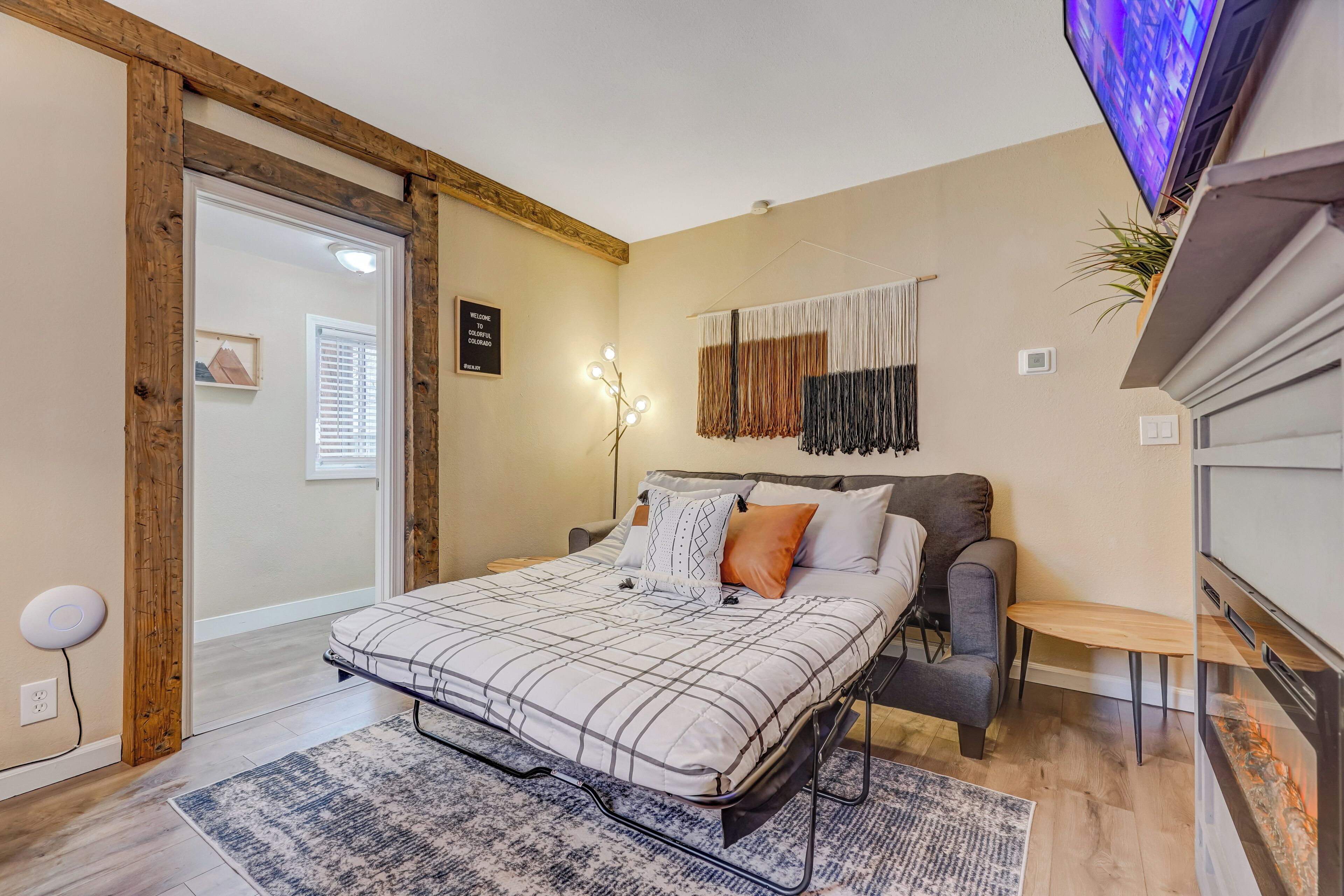 Ein Schlafzimmer mit Bett, Nachttisch, Sessel, Fernseher und Kamin.
