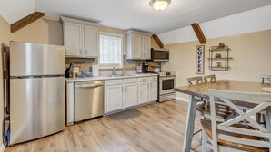 A modern kitchen with stainless steel appliances, white cabinets, and a wooden dining table.