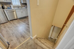 A kitchen with white cabinets, stainless steel appliances, and a wooden floor.