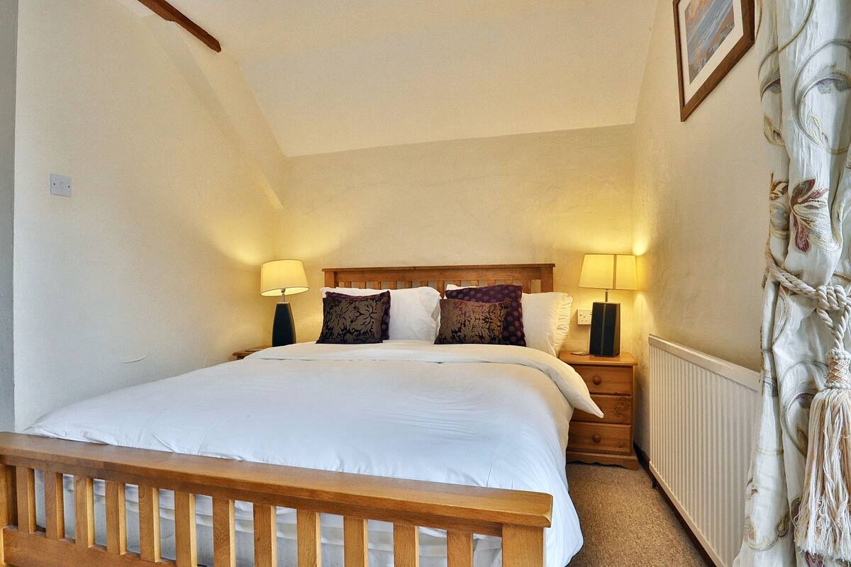 Ein Schlafzimmer mit einem großen Bett, zwei Nachttischen mit Lampen, einem hölzernen Kopfteil und einem Heizkörper.