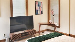 A bedroom with a bed, a TV, a desk, and a ceiling light fixture. - Emerald Brick Home Downtown Indy (Indianapolis)