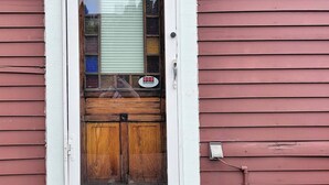 A red house with a white-framed door, a small stone step, and a stone lion statue. - Emerald Brick Home Downtown Indy (Indianapolis)