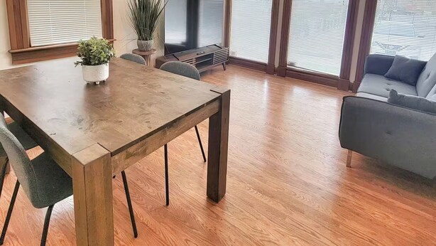 A spacious living area with a wooden dining table, a sofa, and a TV. - Emerald Brick Home Downtown Indy (Indianapolis)