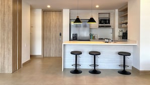 A modern kitchen with a central island, black bar stools, pendant lighting, and built-in appliances. - Morros Zoe by Wynwood House (Cartagena)