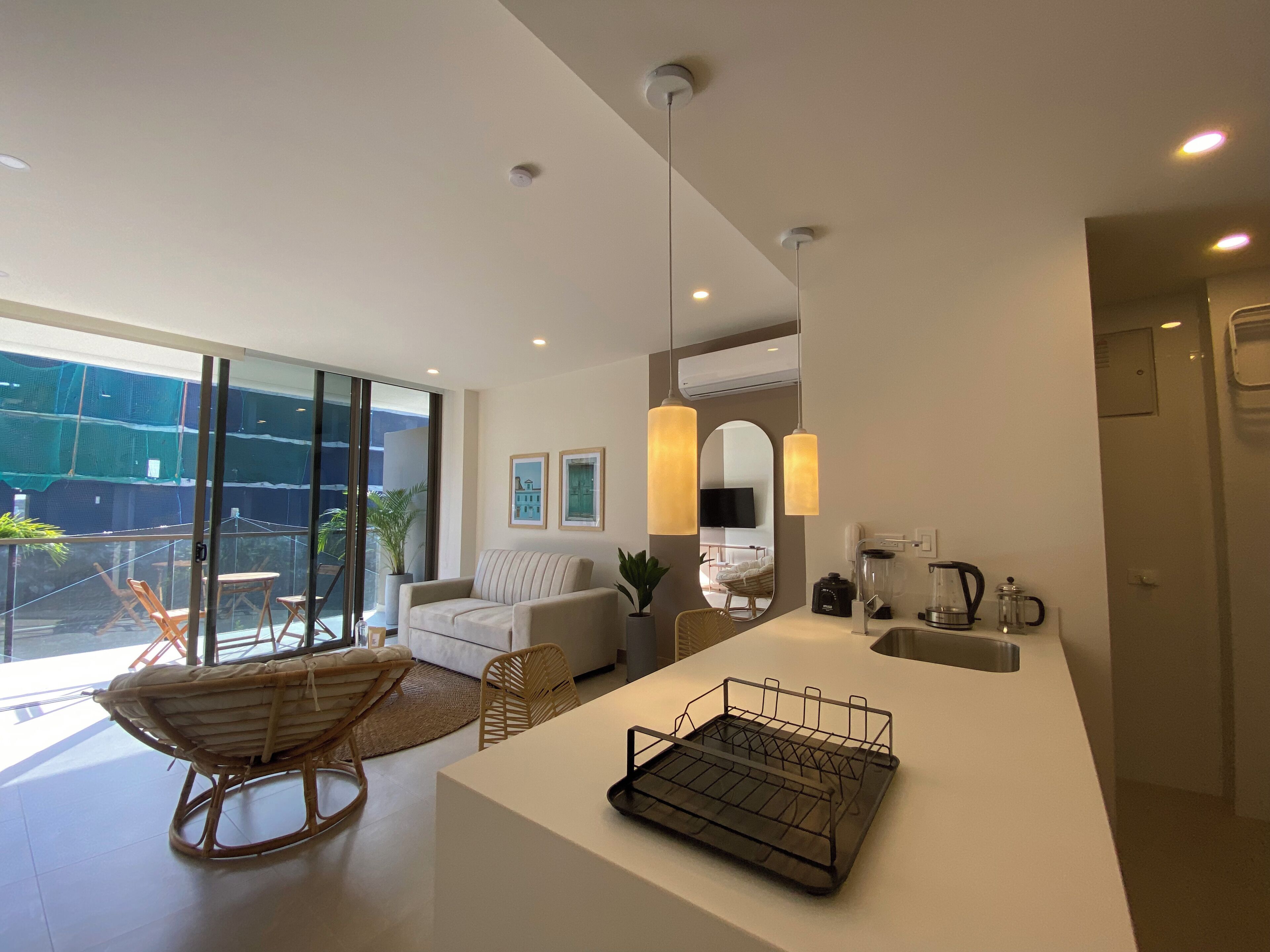 Una sala de estar moderna con un sofá, una mesa de comedor y una zona de cocina con cafetera.