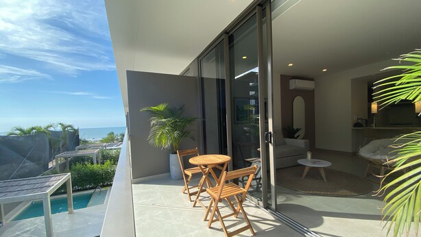 A balcony with a pool, wooden chairs, a table, and a view of the ocean. - Morros Zoe by Wynwood House (Cartagena)