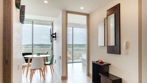 A modern hotel room with a dining area, a large window with a view, a dark wooden console table, and a mounted phone. - Morros Zoe by Wynwood House (Cartagena)