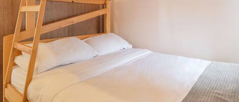 A bunk bed with white bedding and a wooden ladder.