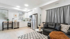 A modern apartment with a kitchen, dining area, and living room. It includes a sofa, a coffee table, and a rug. - Modern/Spacious 2-story 2-bedrm. Free on-site parking. Near all things Niagara! (niagara falls)