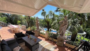 A sunlit outdoor seating area with wicker furniture and a pool in the background. - Ebony & Ivory Suite Home. Probably One of a Kind in Spain (Camargo)