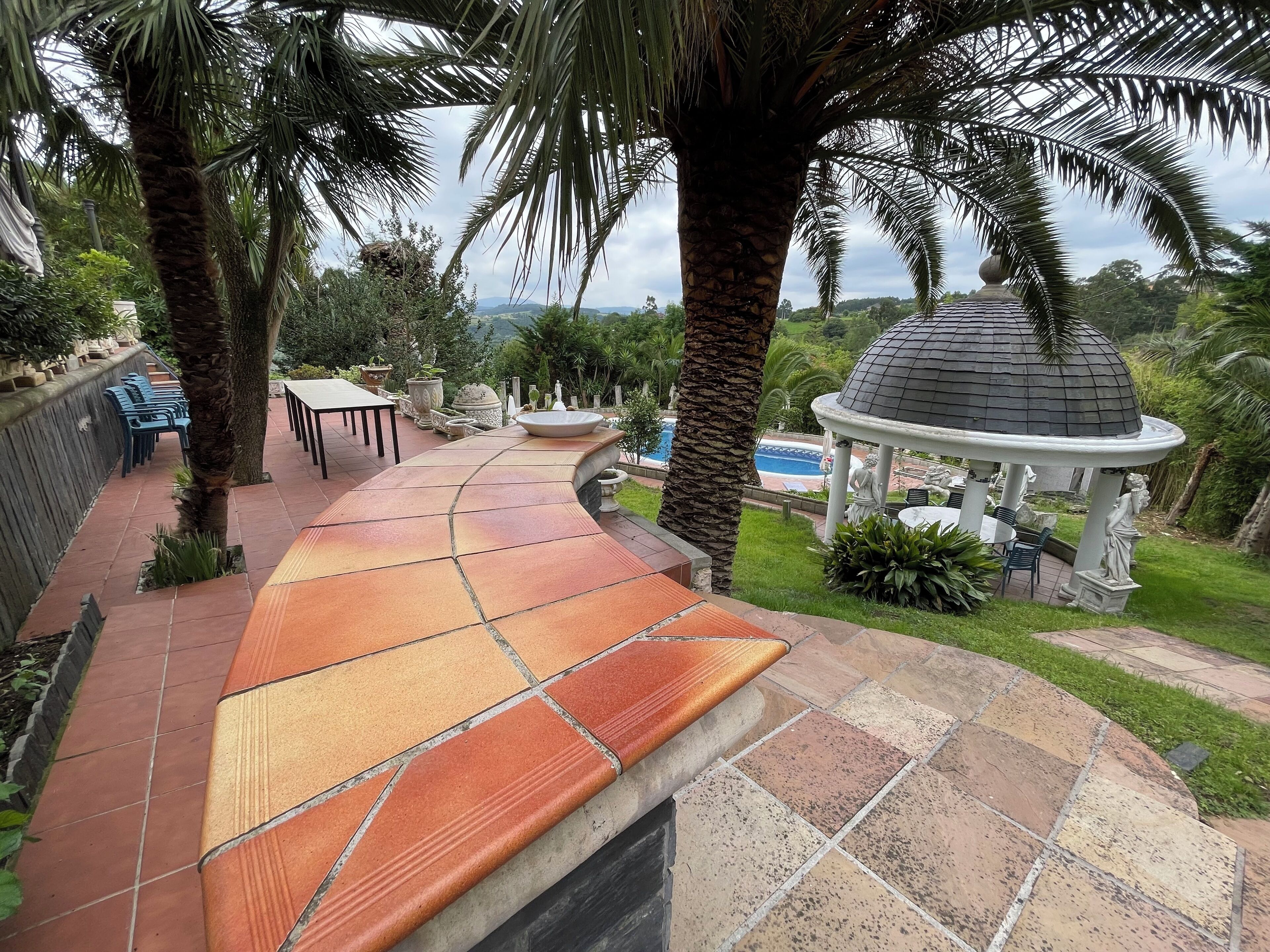 A patio area with a curved tile design, outdoor seating, a gazebo, and a pool.