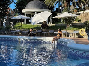 Un área de piscina con un pabellón, sillas de descanso y un fotógrafo.
