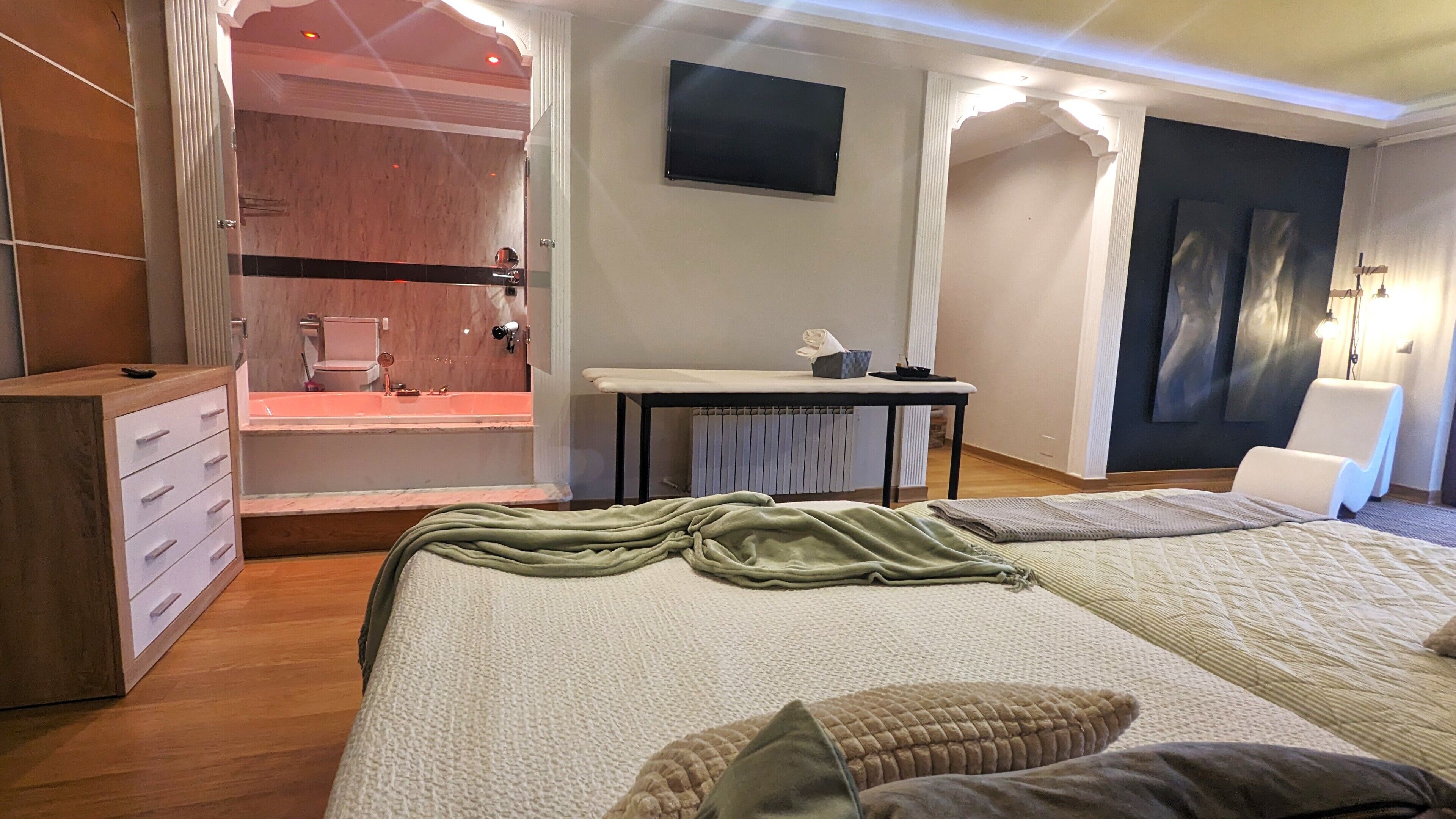 A bedroom with a bed, a desk, a chair, a TV, and a walk-in closet.