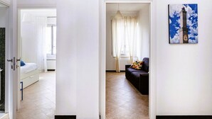 Une chambre d’hôtel avec un lit, un canapé, un tableau et une vue sur l’extérieur, visible à travers une porte ouverte.