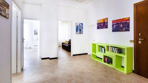 Un couloir avec une bibliothèque verte, une porte et un tableau représentant un paysage urbain accroché au mur.