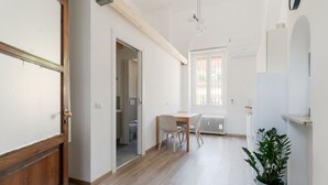 A hallway with a wooden door, a potted plant, a radiator, and a window. - GuestHost - MM2 Lambrate Bright Apartment (Milan)