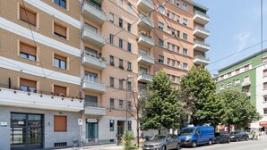 A multi-story residential building with balconies, a parking sign, and a bicycle. - GuestHost - MM2 Lambrate Bright Apartment (Milan)
