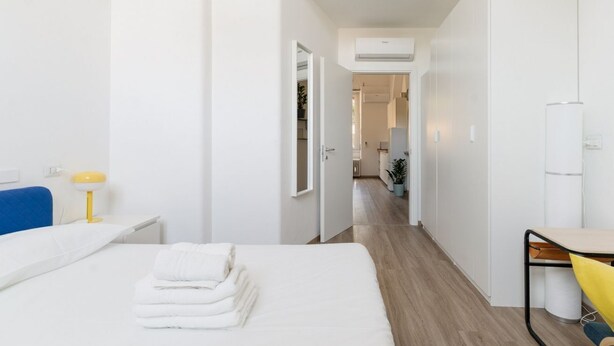 A hotel room with a bed, a desk, a chair, and a small table. - GuestHost - MM2 Lambrate Bright Apartment (Milan)