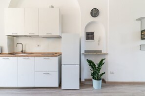 A modern kitchen with white cabinets, a stainless steel sink, a built-in oven, and a refrigerator.