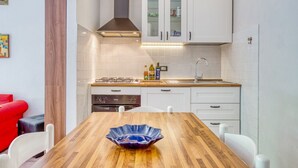 Eine moderne Küche mit weißen Schränken, einem Holzespeisetisch und einem roten Sofa.