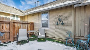 A backyard with a wooden fence, a metal chair, a table, and a decorative wall piece. - Downtown Urban Basecamp - Private Patio, Grill and Fireplace (Colorado Springs)