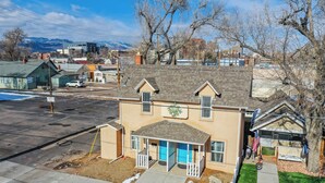A two-story house with a porch, a small front yard, and a white picket fence. - Downtown Urban Basecamp - Private Patio, Grill and Fireplace (Colorado Springs)