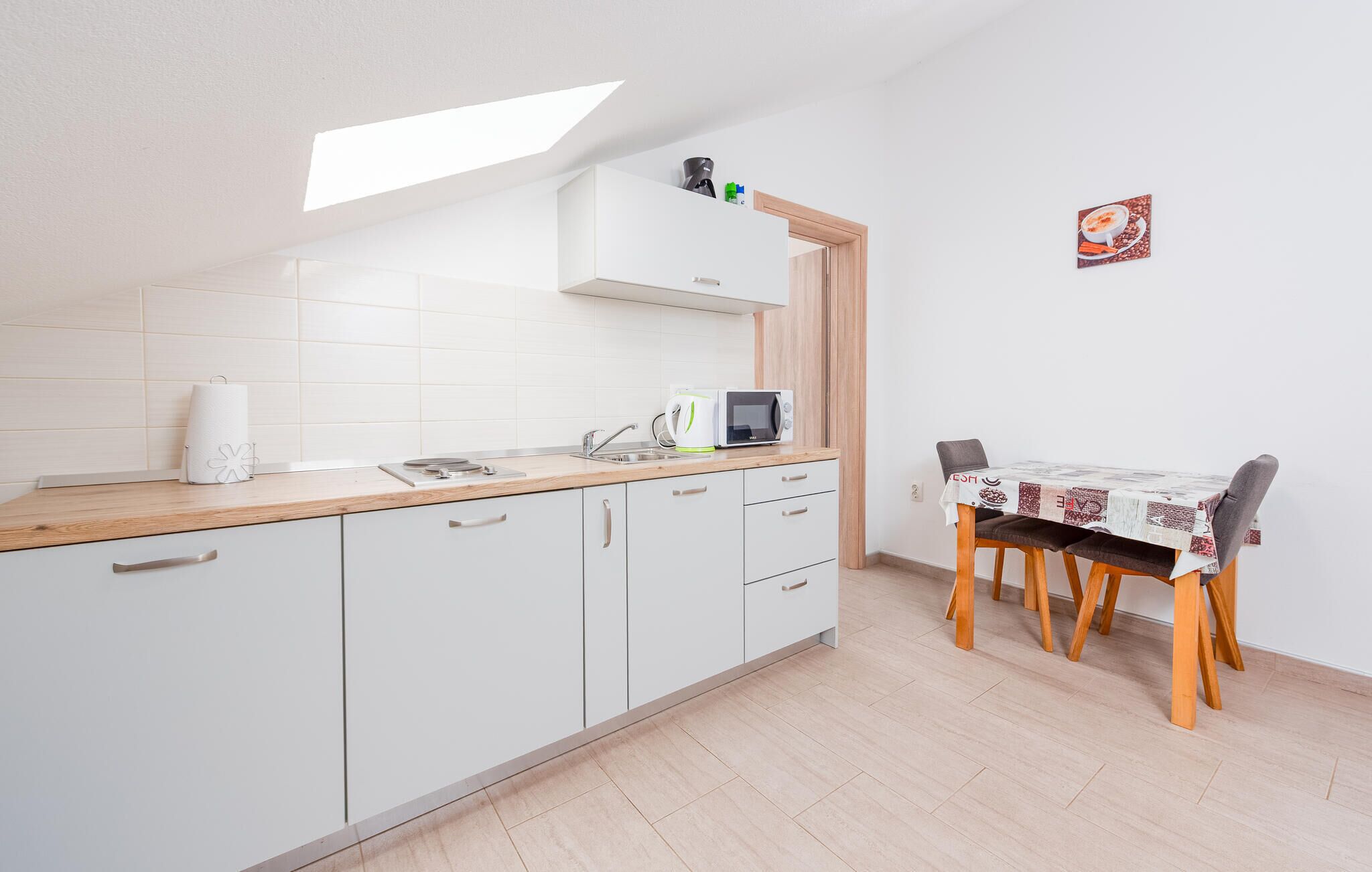 A compact kitchen with white cabinets, a microwave, and a table with chairs.