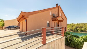 A modern building with a sloped roof, a car parked in front, and a view of a lake. - Cozy apartment in Krusevo with WiFi (Krusevo)