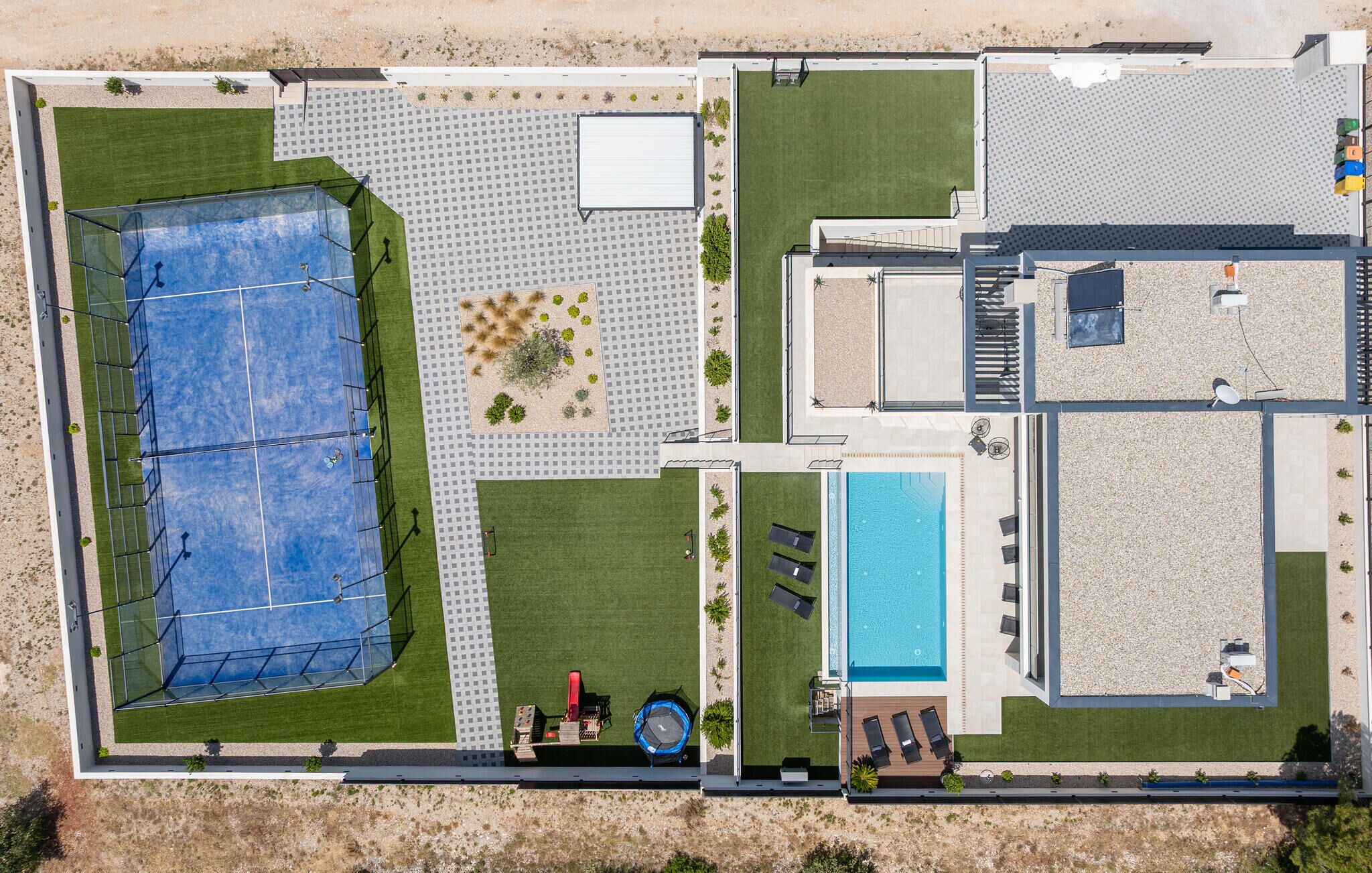 Vue aérienne d’une propriété dotée d’un court de tennis, d’une piscine et d’un patio couvert.