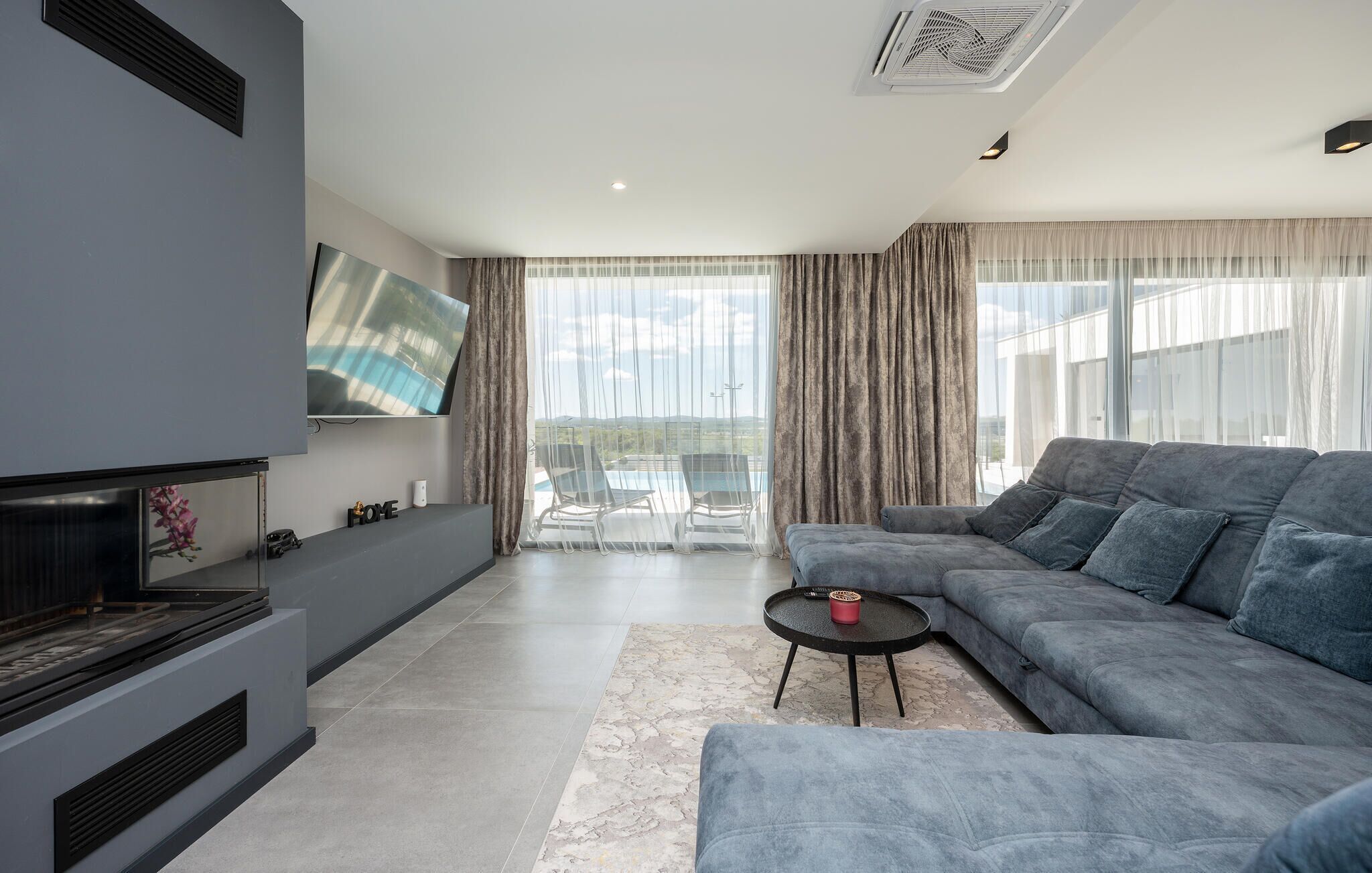 Una sala de estar moderna con un sofá gris, un televisor de pantalla plana y una mesa de vidrio.