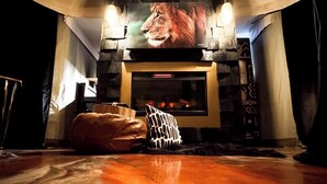 Una sala de estar acogedora con chimenea, un sofá de cuero y un cojín estampado.