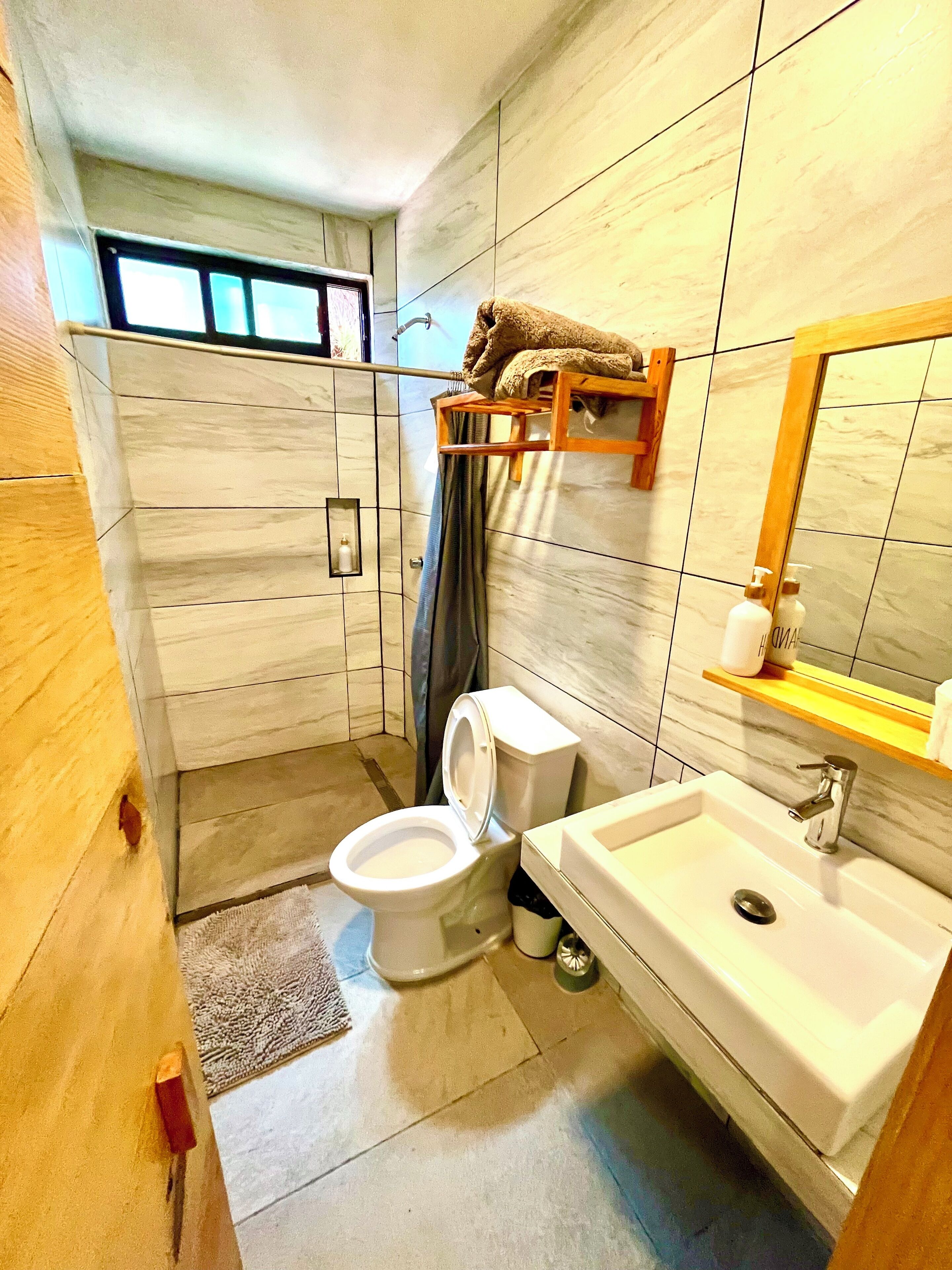 Een moderne badkamer met toilet, wastafel en douche.