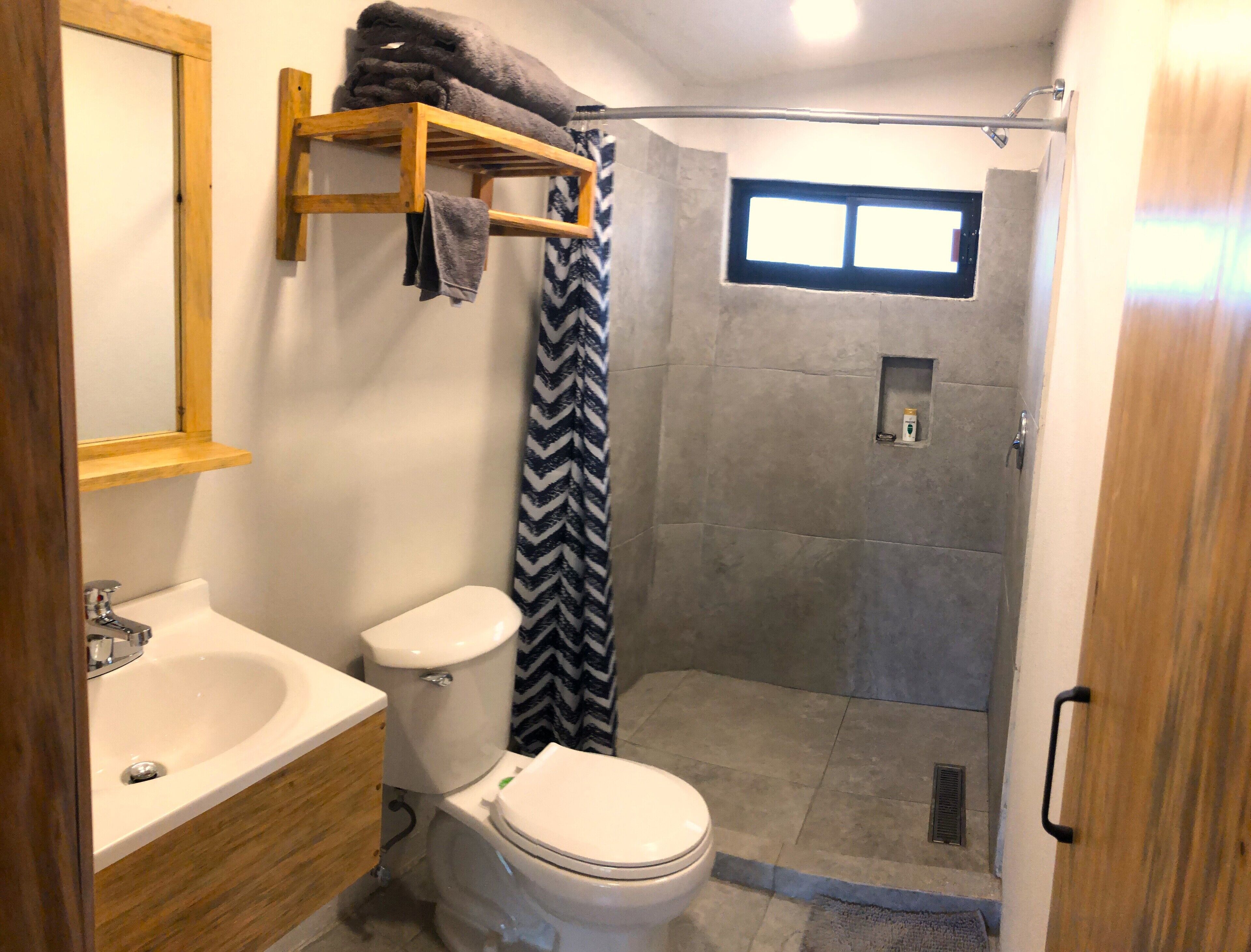A bathroom with a toilet, sink, and shower.