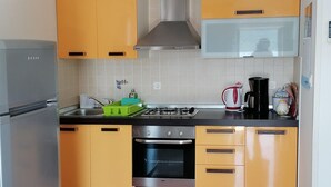 A compact kitchen with yellow cabinets, a stainless steel range, a microwave, and a gas stove.